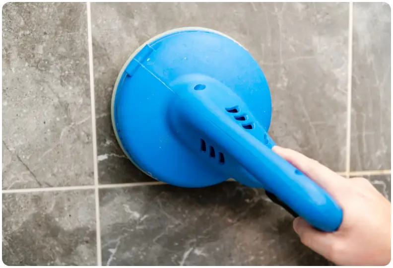 A person is using a blue brush to clean the floor.