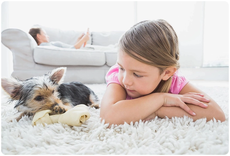 A little girl laying on the floor with her dog.